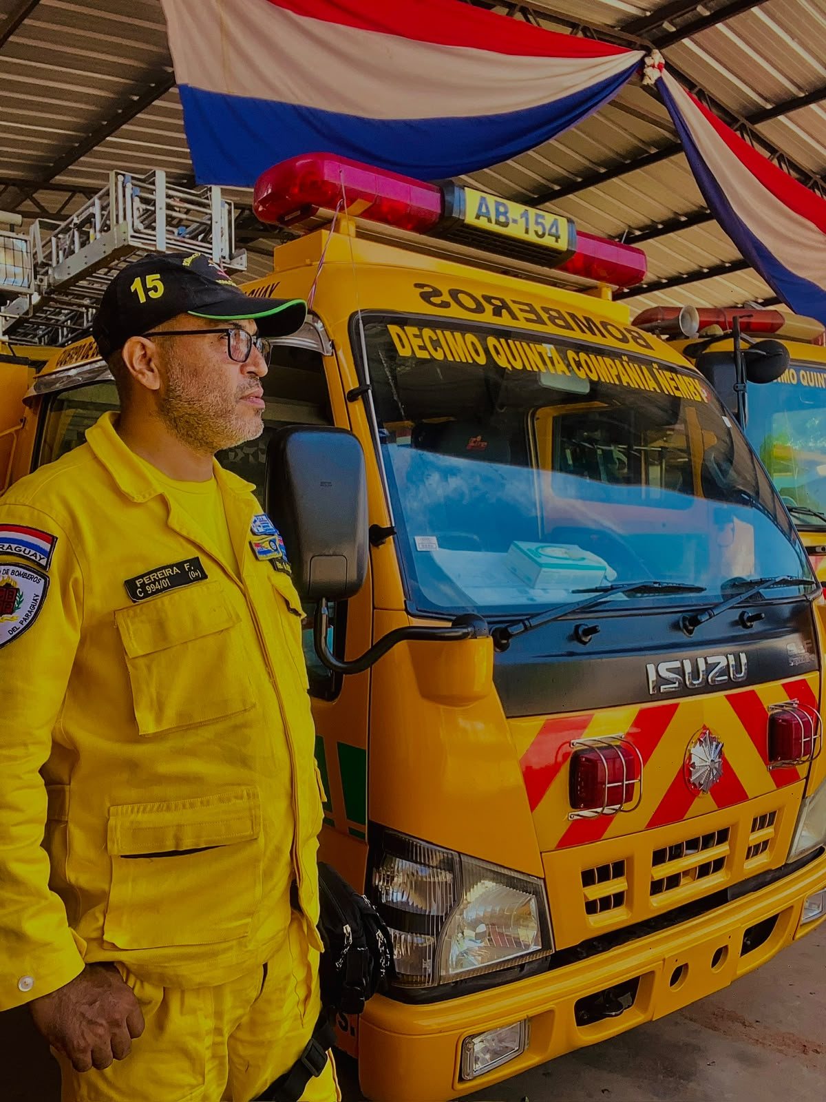 Bombero voluntario de la Décimo Quinta Compañía Ñemby junto a la autobomba AB-154